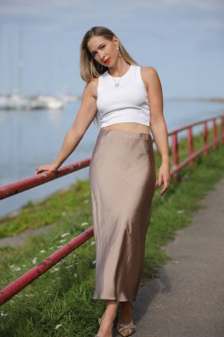 Beyaz bluzlu şehvetli kadın zarif bir şekilde dışarıda poz veriyor.