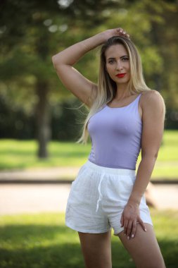 Uzun saçlı, şık bir kadın. Açık havada yaz elbisesi giymiş..