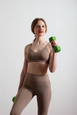 Gri arka planda dambılları olan zayıf genç bir kadın..