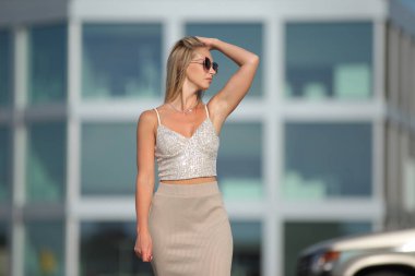 Genç bir kadın şık yaz kıyafetleriyle dışarıda poz veriyor..