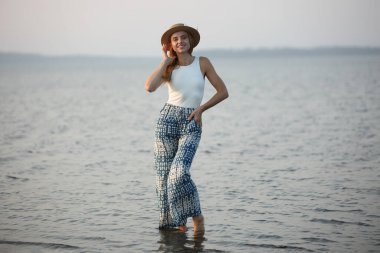 Mutlu kadın plajda çıplak ayakla poz veriyor..