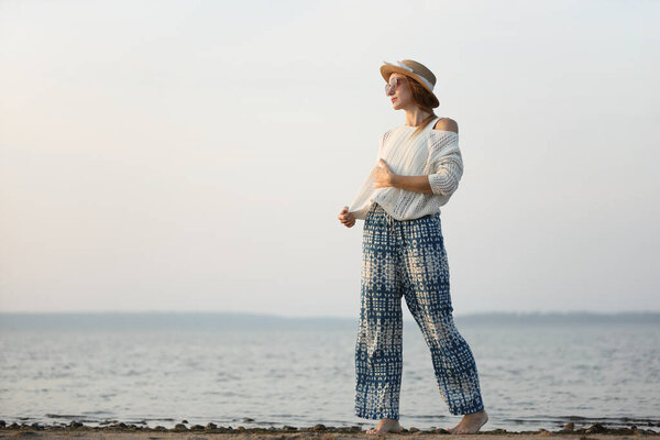 Расслабленная женщина наслаждается спокойной прогулкой на пляже на закате