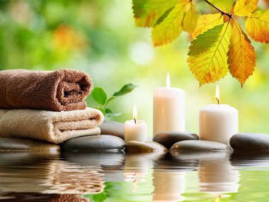Havlular, mumlar, taşlar, yeşil arkaplan ile rahatlatıcı spa sahnesi