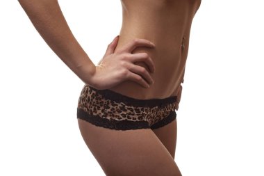 Beyaz arka planda poz veren leopar desenli iç çamaşırlı kadın gövdesi.