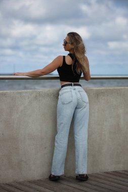 Sıradan kıyafetli bir kadın denize bakıyor.