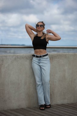 Sıradan kıyafetli bir kadın denize bakıyor.