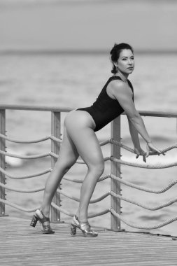 Siyah mayolu, tahta kaldırımda duran kendine güvenen bir kadın.