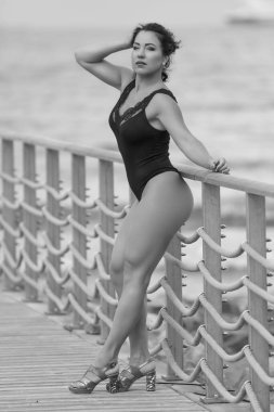 Siyah mayolu, tahta kaldırımda duran kendine güvenen bir kadın.