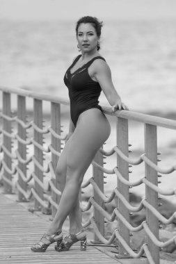 Siyah mayolu, tahta kaldırımda duran kendine güvenen bir kadın.