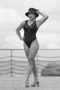 Siyah mayolu, tahta kaldırımda duran kendine güvenen bir kadın.