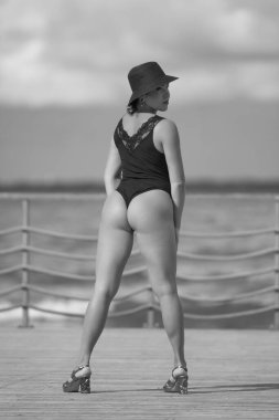 Siyah mayolu, tahta kaldırımda duran kendine güvenen bir kadın.