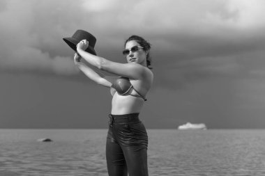 Kendine güvenen bir kadın dramatik gökyüzünün altında suyun içinde duruyor..