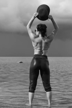 Kendine güvenen bir kadın dramatik gökyüzünün altında suyun içinde duruyor..