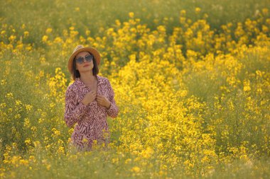 Çiçekli sarı tarlada gülümseyen kadın yaz güneşi altında