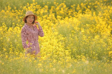 Çiçekli sarı tarlada gülümseyen kadın yaz güneşi altında