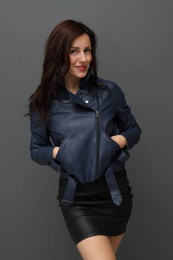 Deri elbiseli, güler yüzlü bir kadın. İçerde rahatça poz veriyor.