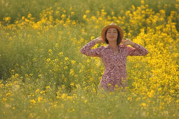 Çiçekli sarı tarlada gülümseyen kadın yaz güneşi altında