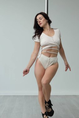 Genç esnek kız pilonun üzerinde pratik yapıyor.