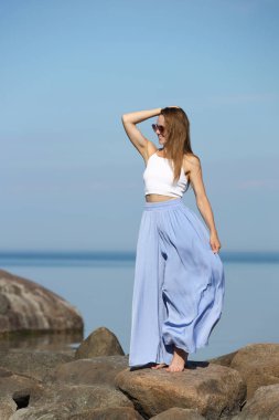 Şık bir kadın güneşli bir yaz gününde deniz manzarasının tadını çıkarıyor..