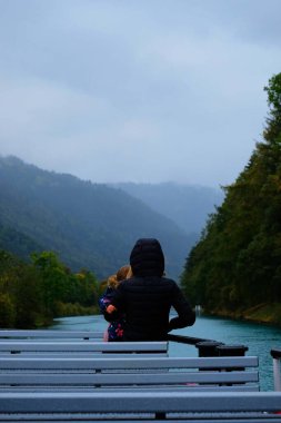  Küçük sevgilisini kucaklayan bir kadın 15 Ekim 2023 'te Interlaken' den batıya, Thun City, İsviçre 'ye giden bir tekne yolculuğunda şefkatle kucaklıyor..