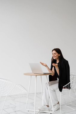 Popüler kız blogcu kanalı istatistiklerine bakıyor ve videolarının bir çok görüntüsünden hoşlanıyor. Dizüstü bilgisayarlı mutlu kadın gülümsüyor ve beyaz arka planda seviniyor.