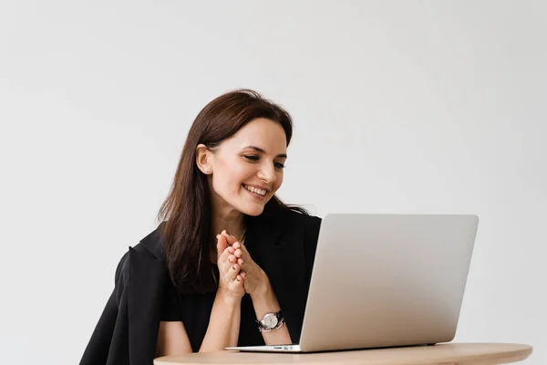 Happy girl chatting with family and friends via video call on white background. Successful business woman with laptop works remotely and laughs with colleagues in online video meeting
