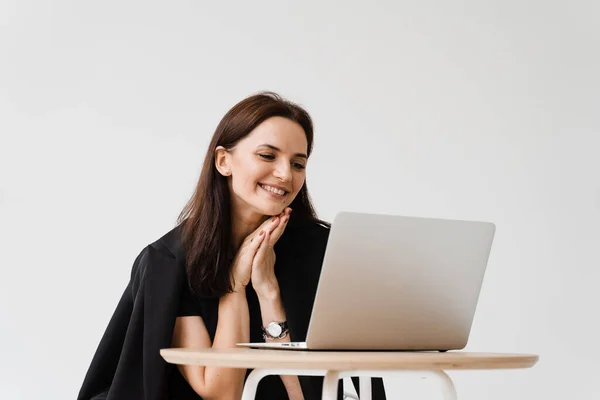 Happy girl chatting with family and friends via video call on white background. Successful business woman with laptop works remotely and laughs with colleagues in online video meeting