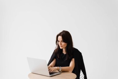 Bilgisayarlı konsantre İngilizce öğretmeni video iletişimi yoluyla çevrimiçi ders alıyor. Mesafe öğrenme. Beyaz arka planda dizüstü bilgisayarda yazıp sohbet eden çekici bir kız.