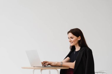 Bilgisayarlı konsantre İngilizce öğretmeni video iletişimi yoluyla çevrimiçi ders alıyor. Mesafe öğrenme. Beyaz arka planda dizüstü bilgisayarda yazıp sohbet eden çekici bir kız.