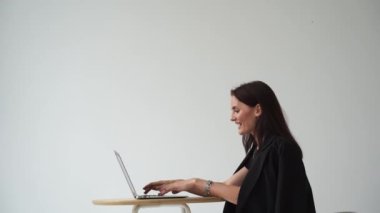 Diz üstü bilgisayarı olan mutlu bir kız 4K video ile video iletişiminde başparmak gösteriyor. Başarılı iş kadını uzaktan çalışıyor ve online video toplantısında meslektaşlarıyla gülüyor.