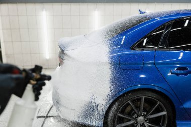 Araba servisinde yıkamanın ikinci aşaması. Araba yıkama makinesi tüm oto yıkamayı yapar. Garajdaki araba cesedine köpük püskürtme işlemi.