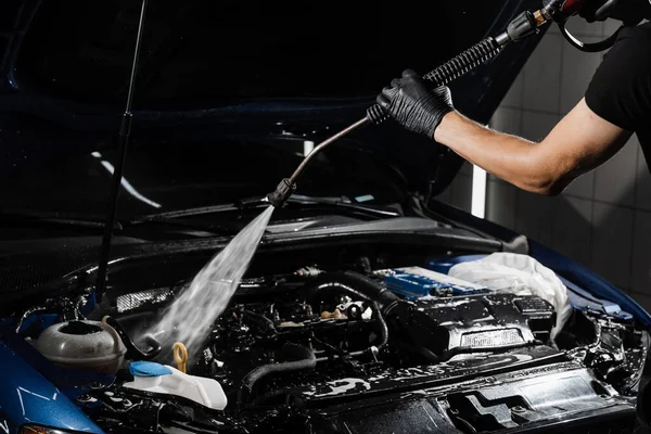 stock image Pouring water on car engine. Washing car engine with spray, brush and detergent in detailing auto service. Detailing cleaning motor from dust and dirt