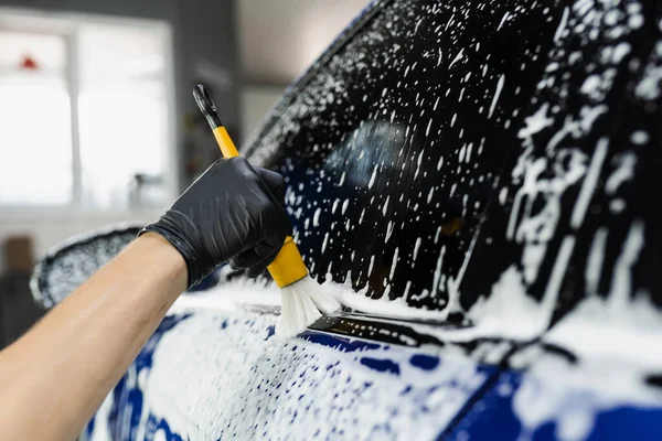 車のディテールサービスで泡と車のボディの手ブラシ洗浄 洗車場労働者が車体を洗う — ストック写真