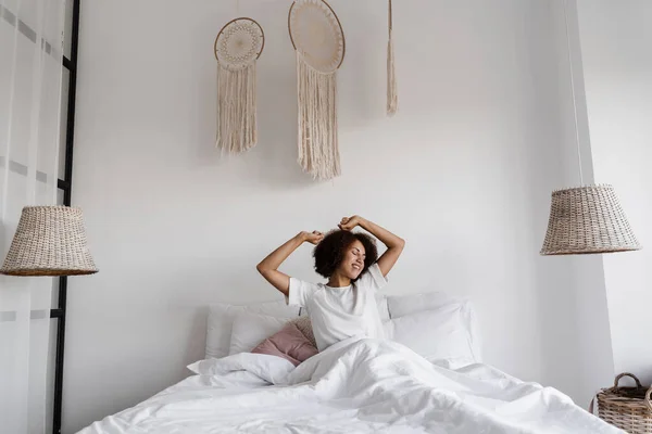 파자마스 침대에서 집에서 아프리카 아프리카 미국인 여성이 깨어나서 아침을 보낸다 — 스톡 사진