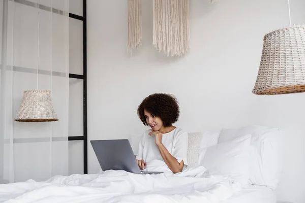 stock image African american girl student study with laptop on the bed in cozy morning at home. Distance learning from home