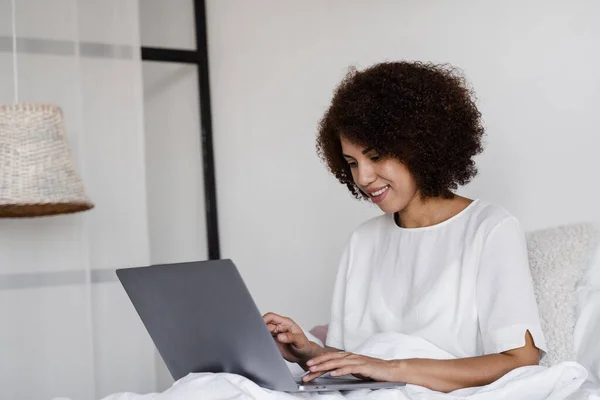 Stock image African american girl student study with laptop on the bed in cozy morning at home. Distance learning from home