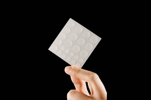 Close-up round acne patch on finger and set of patches in hands on black background. Acne patches for treatment of pimple and rosacea close-up. Facial rejuvenation cleansing cosmetology