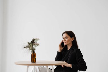 Yoğun bir iş kadını yaşam tarzı. Beyaz kafede telefonla konuşan çekici bir kız. Akıllı telefon kullanan aile ve arkadaşlarla iletişim