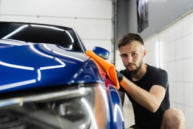 Oto servisinde mikrofiberle kurutulan el arabası. Araba yıkadıktan sonra temizlikçi kuru araba.