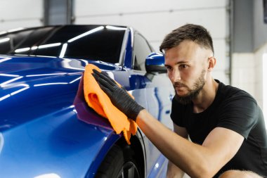 Oto servisinde mikrofiberle kurutulan el arabası. Araba yıkadıktan sonra temizlikçi kuru araba.