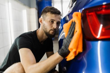 Oto servisinde mikrofiberle kurutulan el arabası. Araba yıkadıktan sonra temizlikçi kuru araba.