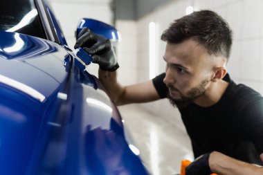 Detaylı servis çalışanı arabaya seramik koruyucu sıvı uygular. Arabayı çiziklerden korumak için nano seramik koruyucu palto.