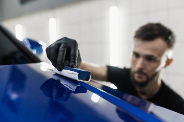 Detaylı servis çalışanı arabaya seramik koruyucu sıvı uygular. Arabayı çiziklerden korumak için nano seramik koruyucu palto.