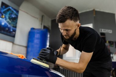 Yörüngesel cilalayıcı sürtünmeli araba cilası çizikleri silmek için. Otomobil servisi çalışanı araba için son cilalamayı yapıyor