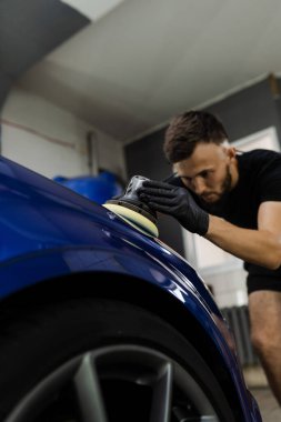 Yörünge cilasıyla cilalanan sert balmumu araba yakın plan çizikleri silmek için. Otomatik servisin detaylandırılmasında çalışma süreci