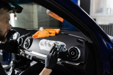 Arabada fırça kullanarak köpük ve deterjan temizleme. Otomotiv temizleme servisinde çalışan bir işçi. Araç iç dekorasyonu