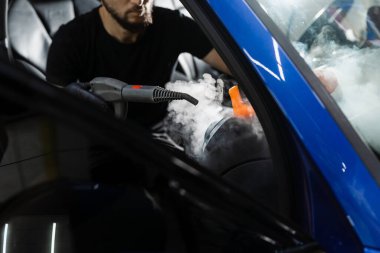 Hava sisteminde buhar temizliği. Otomotiv temizleme servisinde çalışan bir işçi. Araç iç dekorasyonu