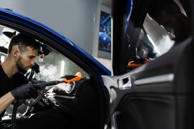 Hava sisteminde buhar temizliği. Otomotiv temizleme servisinde çalışan bir işçi. Araç iç dekorasyonu