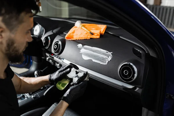 Arabada fırça kullanarak köpük ve deterjan temizleme. Otomotiv temizleme servisinde çalışan bir işçi. Araç iç dekorasyonu