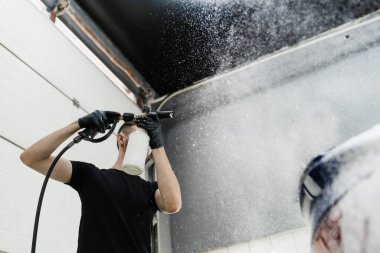 Garajdaki araba cesedine köpük püskürtme işlemi. Araba servisinde yıkamanın ikinci aşaması. Araba yıkama makinesi tüm oto yıkamayı yapar.